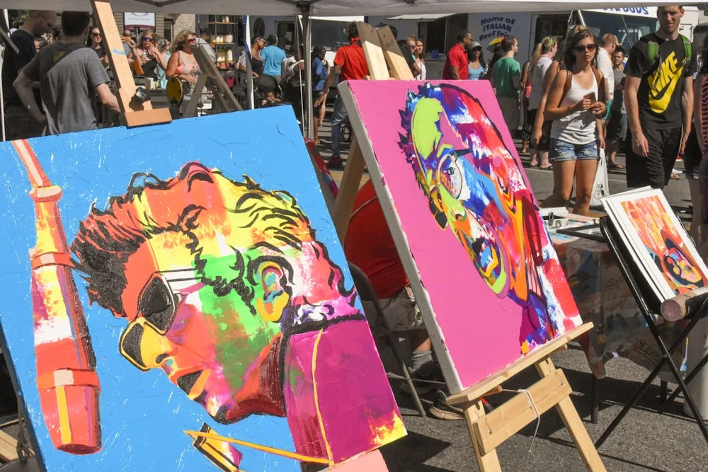 Artist working in a bright studio surrounded by colourful paintings and supplies