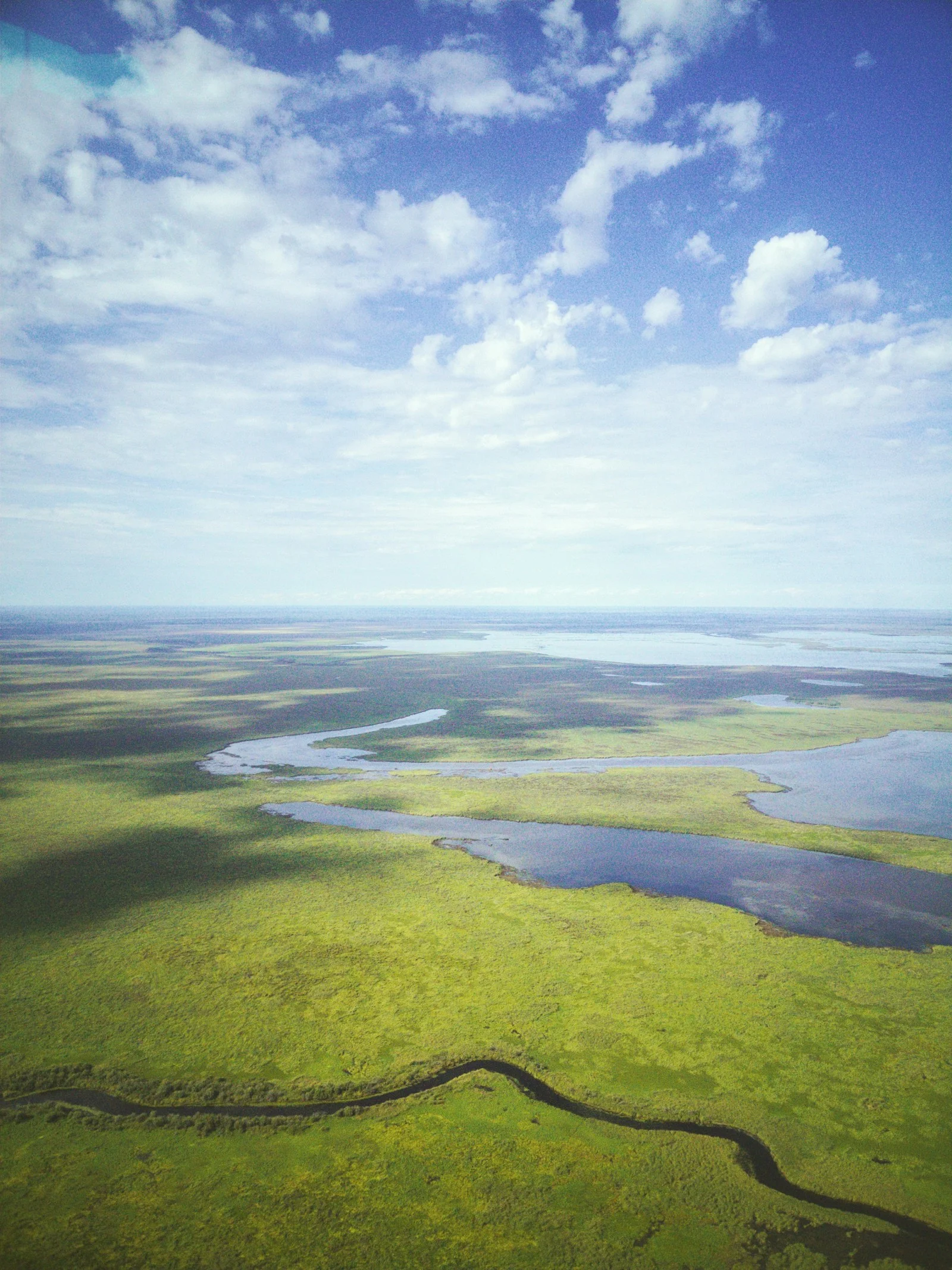 Vast golden prairie grassland stretching to the horizon under a wide Saskatchewan sky