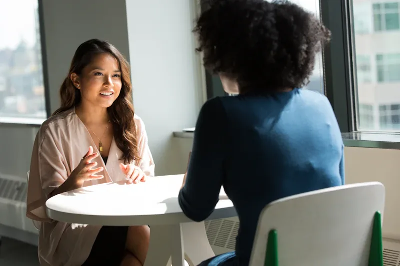 A group of adults sitting together in a warm community space, in conversation